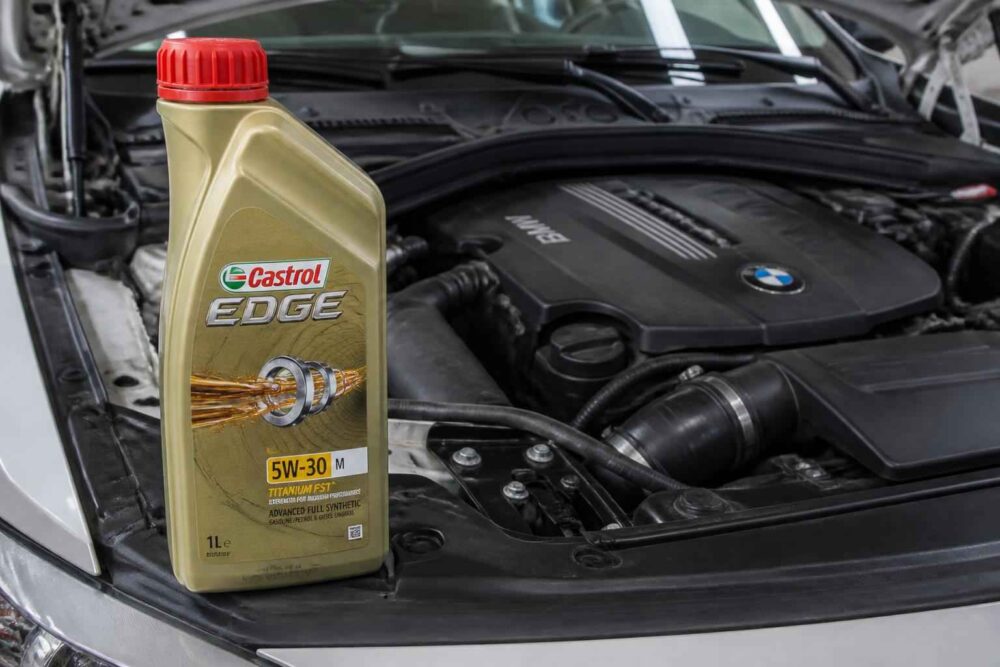 Butelka oleju Castrol EDGE 5W-30 przed otwartą komorą silnika BMW