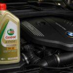 Butelka oleju Castrol EDGE 5W-30 ustawiona obok silnika BMW pod maską samochodu