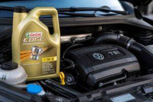 Butelka oleju Castrol Edge 5W-30 stojąca obok silnika Volkswagena TSI.