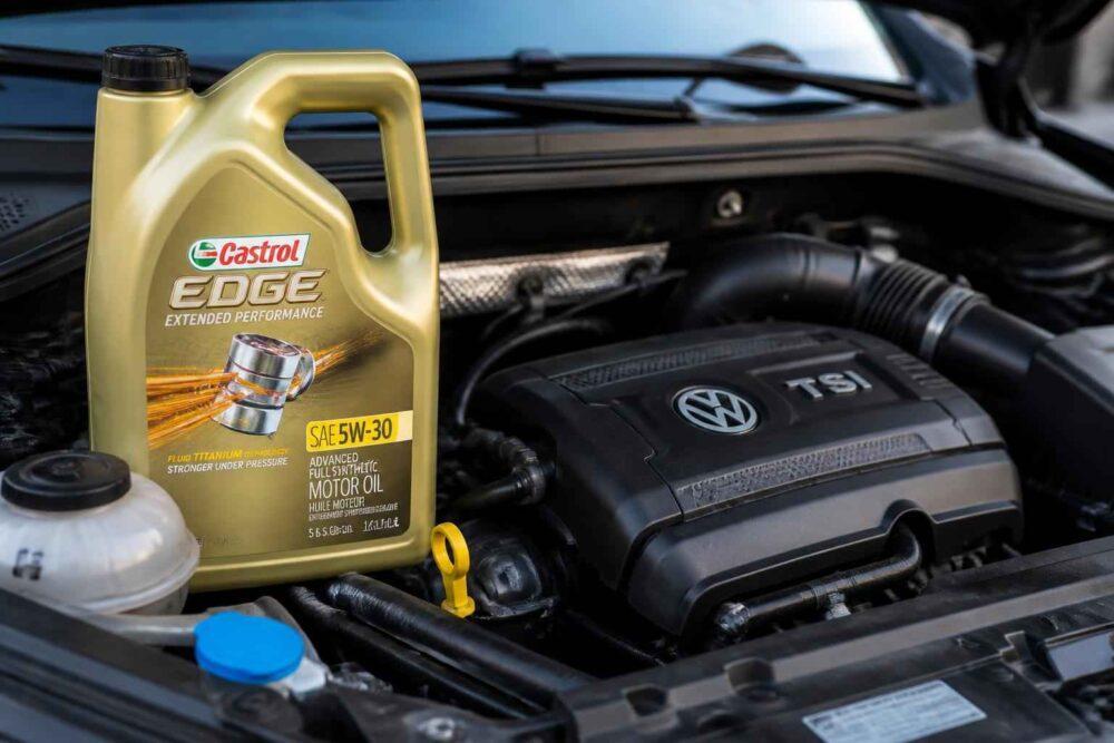 Butelka oleju Castrol Edge 5W-30 stojąca obok silnika Volkswagena TSI.