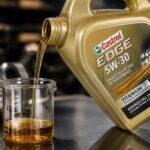 Kanister oleju Castrol Edge 5W-30 przelewa olej do szklanego naczynia miarowego w warsztacie samochodowym
