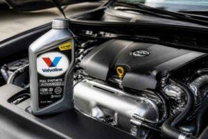 Butelka oleju Valvoline stojąca obok otwartego silnika samochodowego