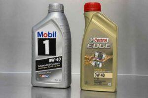 Butelki olejów silnikowych Mobil 1 i Castrol Edge 0W-40 stojące obok siebie na metalowej powierzchni