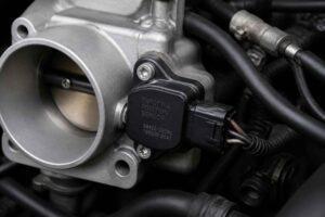 Metalowa przepustnica silnika z zamontowanym czujnikiem położenia i przewodami elektrycznymi