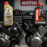 Dwa silniki motocyklowe z butelkami olejów Castrol Power1 i Motul 7100 w warsztacie
