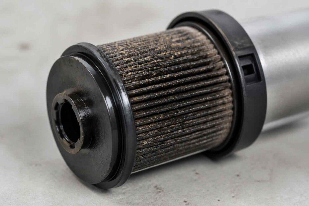 Cylindryczny filtr hydrauliczny z widocznym nagromadzeniem brudu na wkładzie filtracyjnym